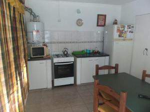 La cuisine est équipée de placards blancs et d'un four avec plaques de cuisson. dans l'établissement Apartamento El Calvario 4, à Tandil