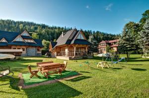 un patio con mesa de picnic de madera y parque infantil en Domek drewniany luxury cottage Dabrowa en Zakopane