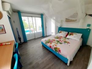 ein Schlafzimmer mit einem blauen Bett mit Blumen darauf in der Unterkunft SAINTE-LUCE 2 T1 HIBISCUS et COLIBRIS in Sainte-Luce