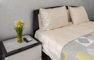 1 dormitorio con 1 cama con un jarrón de flores sobre una mesa en Golden Violin ! Apartments Lviv S, en Leópolis