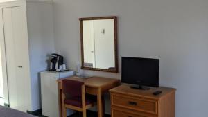 a room with a desk with a television and a mirror at Valois Motel & Restaurant in Mattawa