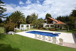a backyard with a swimming pool and chairs and a house at Quinta La Constanza in Tababela
