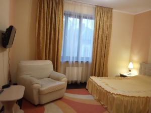 a hotel room with a chair and a bed at готель ДежаВю in Berdychiv