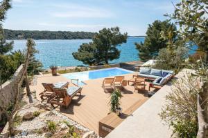 a house with a swimming pool next to the water at Villa del Mar Deluxe in Mali Lošinj