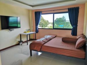 een slaapkamer met een bed en een groot raam bij BN Resort in Ban Nong Chum Saeng