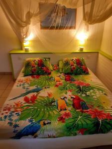 a bed with a colorful blanket with birds on it at SAINTE-LUCE 2 T1 HIBISCUS et COLIBRIS in Sainte-Luce