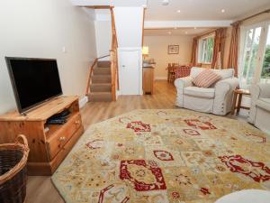 sala de estar con TV de pantalla plana y alfombra en The Cottage At Barrow Mead, en Bath