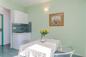 une cuisine avec une table et un vase de fleurs. dans l'établissement Apartments Zdenka, à Okrug Donji