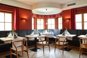 a dining room with tables and chairs and red walls at Nebelhorn Relaxhotel in Obermaiselstein