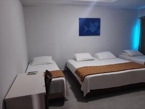 Cette chambre comprend 2 lits et une table. dans l'établissement PEDRA BONITA PRECIOSO HOTEL ltda, à Itaboraí