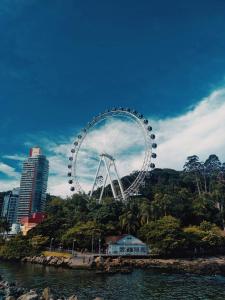 une grande roue ferris sur une colline à côté de l'eau dans l'établissement APTO BEIRA MAR BALNEARIO CAMBORIU, à Balneário Camboriú