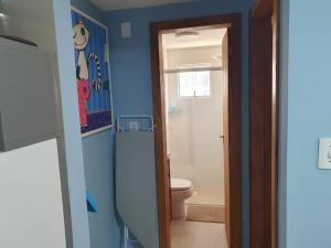 La salle de bains bleue est pourvue de toilettes et d'une porte. dans l'établissement APTO BEIRA MAR BALNEARIO CAMBORIU, à Balneário Camboriú