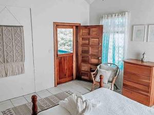 Un dormitorio con una cama y una silla y una ventana. en Vacation Home Blue Lotus- Gold Standard Certified, en Caye Caulker