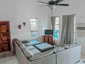 Una sala de estar con un sofá y un ventilador de techo. en Vacation Home Blue Lotus- Gold Standard Certified, en Caye Caulker