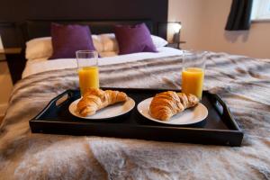 a tray with two cups of orange juice and croissants on a bed at Stunning Holiday Home Woodcote View in Oakworth