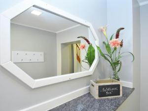 a mirror on a wall with a vase with flowers at Holiday home in Elbingerode with garden in Rübeland