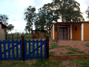 una cerca azul frente a una casa pequeña en Viudita del Diablo, en Punta del Diablo