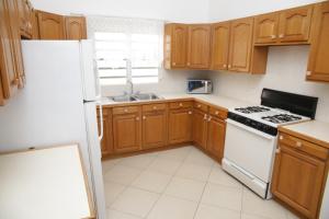 uma cozinha com armários de madeira e um frigorífico branco em Breezee em Long Path