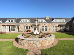 a large stone house with a fountain in the yard at Tyn Towyn - Ty Piws in Trearddur
