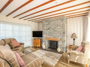 a living room with two couches and a stone fireplace at Tyn Towyn - Ty Piws in Trearddur