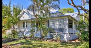a white house with a white fence and palm trees at Arcadia House in Byron Bay