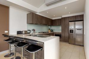 a kitchen with a white counter top and wooden cabinets at Seaside Luxury Accommodation in the Heart of Rye in Rye