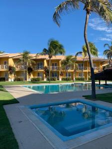 un complejo con piscina y palmeras en Bouganville Hotel, en Beberibe