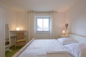 een slaapkamer met een groot wit bed en een raam bij Marschblick in Rantrum