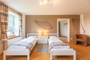 a bedroom with two beds and a chair at Osterhof in Galmsbüll