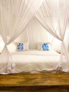 una camera da letto con un letto bianco con tende bianche di Pousada Villa dos Corais a Trancoso