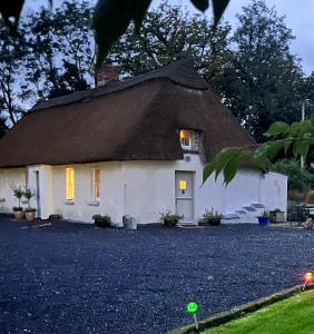 Casa con techo de paja y entrada de grava en New Thatch Farm, knocklong, Limerick, en Cross of the Tree