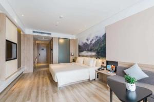 Atour Hotel Hangzhou Future Technology City Haichuang Park في هانغتشو: غرفه فندقيه بسرير واريكه