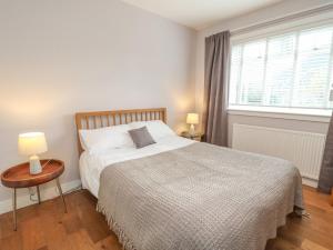 a bedroom with a bed and a table and a window at Holly Cottage in Glencoe