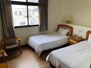Habitación de hotel con 2 camas y ventana en 金麗麗大飯店 en Jinning