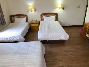 2 camas en una habitación de hotel con sábanas blancas en 金麗麗大飯店, en Jinning