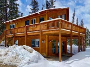 a log cabin with a wrap around deck in the snow at NEW HOT TUB! Secluded, tucked away cabin in Fairplay