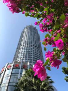 un edificio alto con flores rosas delante en Swissotel Foshan, Guangdong, en Foshan