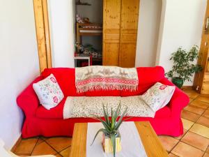 un sofá rojo en una sala de estar con mesa en Rez de jardin de chalet bois , calme et verdure !, en Saint-Martin-Vésubie