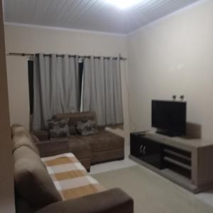 een woonkamer met een bank en een flatscreen-tv bij Casa Acomodação in Campos dos Goytacazes