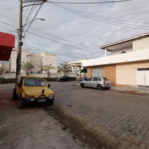 een gele auto geparkeerd op een straat met twee auto's bij Casa Acomodação in Campos dos Goytacazes