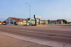 uma rua vazia numa pequena cidade com um posto de gasolina em Roadrunner Lodge Motel em Tucumcari