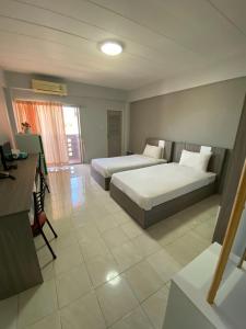 um quarto de hotel com duas camas e uma secretária em Burapha Bangsaen Garden Apartment em Bangsaen