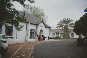 a white house with a palm tree in front of it at Lydenburg Manor Guest House in Lydenburg