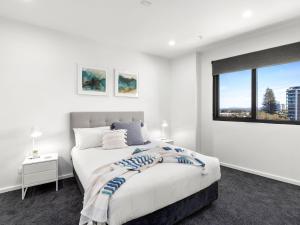 een witte slaapkamer met een bed en een raam bij Cove 401 in Forster