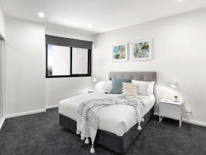 een witte slaapkamer met een bed en een raam bij Cove 401 in Forster