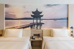 Atour Hotel Hangzhou Future Technology City Haichuang Park في هانغتشو: سريرين في غرفة الفندق مطلة على الماء