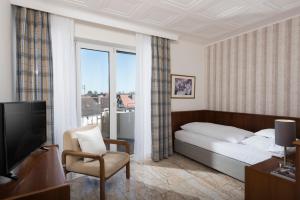 フランクフルト・アム・マインにあるホテル ハルハイマー ホフのベッド、椅子、テレビが備わるホテルルームです。