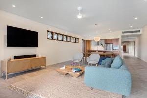 a living room with a blue couch and a tv at Azure at Funnel Bay in Airlie Beach