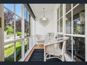 porche con 2 sillas, mesa y ventanas en Creek Cottage Bed and Breakfast Traralgon en Traralgon