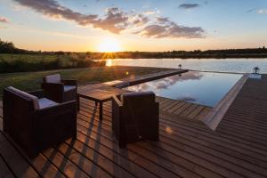 a swimming pool on a wooden deck with a sunset at Chambre d’hotes Le Grand Fourneau in Lassay-sur-Croisne